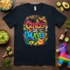 Cinco de Mayo text design with festive Mexican graphics including sombreros, maracas, guitar, and avocados on a black t-shirt