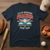 Navy t-shirt featuring "City of Rockford Peaches Womens Professional Baseball Team Estd 1943" text with winged baseball graphic