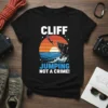 Black t-shirt with "CLIFF JUMPING NOT A CRIME!" text, featuring a sunset graphic of a person diving from a cliff