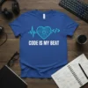 Blue t-shirt with "CODE IS MY BEAT" text, heart-shaped circuit board, heartbeat line, and code symbols