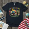 T-shirt with "COLOR OUR WORLD SUMMER reading 2025" text and vibrant summer graphics including sun, beach, and books
