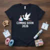 Coming Soon 2026 T-Shirt with a stork carrying baby bundles, announcing a pregnancy