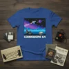 Commodore 64 text with pixel art spaceship, joysticks, and planets on a blue t-shirt
