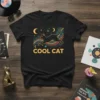 Black t-shirt with "COOL CAT" text and a black cat silhouette jumping, surrounded by stars and a crescent moon, in