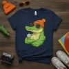 Cool muscular alligator wearing orange beanie and sunglasses, holding a drink, on a navy blue t-shirt