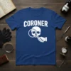 Coroner T-Shirt with white text "CORONER" above a white graphic of a skull being examined with a magnifying glass