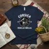 Navy blue t-shirt featuring "CORSICA ISULLA BELLA" text with a circular mountain graphic and profile of a man wearing a