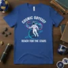 Astronaut floating in space with rings around planets, text "COSMIC ODYSSSY REACH FOR THE STARS" on a blue t-shirt