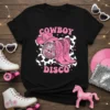 Cowboy Disco text with pink cowboy hat, pink cowboy boots, and disco ball on a black t-shirt graphic