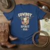 Cowboy Spirit USA text with a longhorn skull and American flag shield graphic on a blue t-shirt