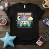 Black t-shirt with "COZY VIBES" repeated in pastel colors, featuring a cute smiling video game controller, moon, and cloud