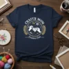 Crafty Mom Creators Club design with hands sewing a heart, knitting needles, scissors, and yarn on a navy blue t-shirt