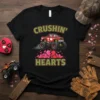 Crushin' Hearts text with a red monster truck graphic crushing pink hearts, on a black t-shirt