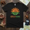 Black t-shirt with Côte d'Ivoire flag colors, tree, and tribal masks design. Features text "CÔTE D'IVOIRE"