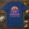 Retro graphic tee with "Cupcake Kingdom" text, featuring cupcakes and a cityscape under a sunset