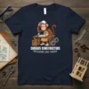 Curious Constructors Building Big Ideas t-shirt featuring a monkey wearing overalls and a cap, sitting at a desk with blueprints