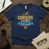 Cursive Is My Secret Code text design on a navy blue t-shirt, featuring a quill and circuit board graphic
