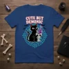 Cute But Demonic t-shirt design with a black cat drinking from a skull goblet, surrounded by occult symbols and bats