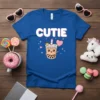 Blue t-shirt with the word "CUTIE" in white and pink text, featuring a kawaii bubble tea cup with a crown