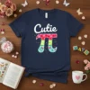 Cutie Pi t-shirt design with white text "Cutie" above a colorful pi symbol featuring hearts, flowers, and butterflies
