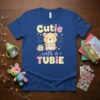 Cutie with a TUBIE t-shirt design featuring a smiling bear with a feeding tube and a medical bag, surrounded by