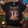 Día De Los Muertos t-shirt with sugar skull couple playing guitar and maracas, surrounded by festive decorations and candles