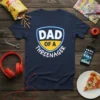 Navy blue t-shirt with "Dad of a Threenager" text in a shield design, white and yellow accents