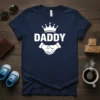 Navy blue t-shirt with white text "DADDY" above a crown and handshake graphic, representing fatherhood