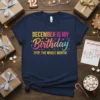December Is My Birthday (Yep, The Whole Month) text design with a colorful gradient birthday graphic on a navy t-shirt
