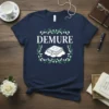 Demure t-shirt with white text and a book graphic surrounded by floral elements