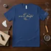 Navy blue t-shirt with "DEMURE Mindful" text and delicate floral and star graphic in gold
