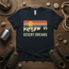 Desert Dreams t-shirt with a retro sunset landscape featuring cacti and mesas, navy blue shirt