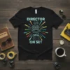 Director On Set text with film camera, megaphone, and clapperboard graphics on a black t-shirt