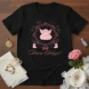 Black t-shirt with "Divine Angel" text and a pink cherub graphic surrounded by a floral wreath and hearts