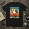 Dizzy Owl graphic t-shirt with a cartoon owl looking confused on a branch against a vintage sunset background