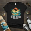 Black t-shirt featuring "DOG SKATE ADVENTURES RIDE THE WAVE" text with a dog skateboarding on a wave, palm trees, and