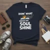 Doin' What Makes My Soul Shine quote with an open book and sun graphic on a navy t-shirt
