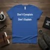 Blue t-shirt with white text "Don't Complain Don't Explain" and a blue mountain and arrow graphic
