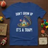Don't Grow Up It's A Trap! quote on a blue t-shirt with a castle inside a bear trap graphic