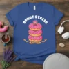 Donut Stress text above a stack of three pink glazed donuts in a yoga meditation pose on a blue t-shirt