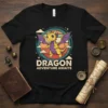 Dragon Adventure Awaits text with a cute yellow dragon graphic on a black t-shirt, vintage sunset background