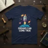 Dreams Can Come True quote with a cartoon rocket ship launching into space, stars, and planets on a navy t-shirt