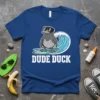 Dude Duck T-Shirt featuring a cartoon duck wearing sunglasses, surfing a wave, with bold white text "DUDE DUCK"