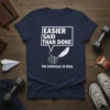 Navy t-shirt with white text reading "Easier Said Than Done" above a graphic of a rock and feather, with "The