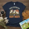 Easily Distracted By Baby Goats t-shirt design featuring cute cartoon goats and a barn graphic