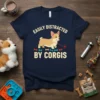 Navy t-shirt with "Easily Distracted By Corgis" text and a cartoon corgi chasing a laser pointer