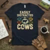 Easily Distracted By Cows text design with vintage cow illustrations and distressed font on a navy t-shirt