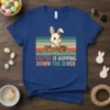Easter Is Hopping Down The River text with a cute cartoon bunny rowing a boat, retro color stripes background