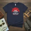 Navy t-shirt with "Eat Sleep Repeat" text and airplane graphic in a circular design, featuring mountains and a plane