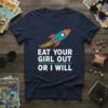 Navy blue t-shirt with white text "EAT YOUR GIRL OUT OR I WILL" and a teal rocket graphic